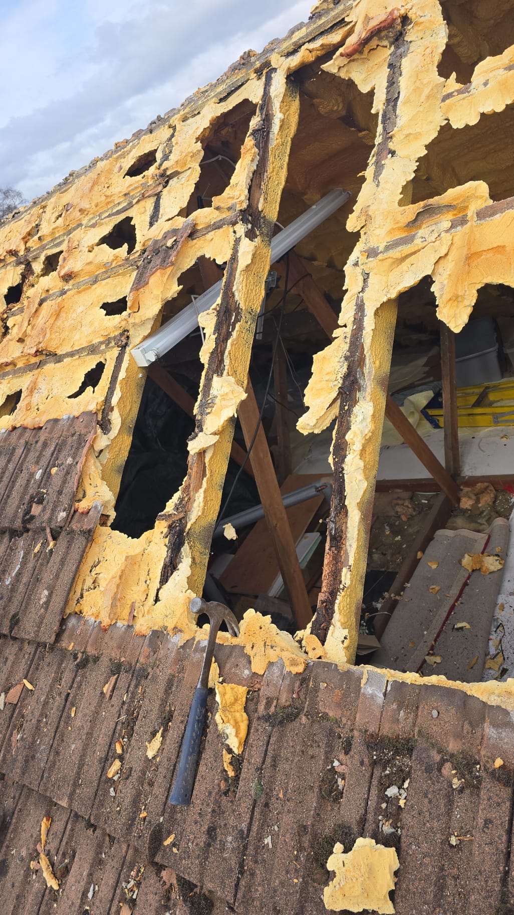 Roof exterior with foam debris and missing tiles where the covering had broken down.